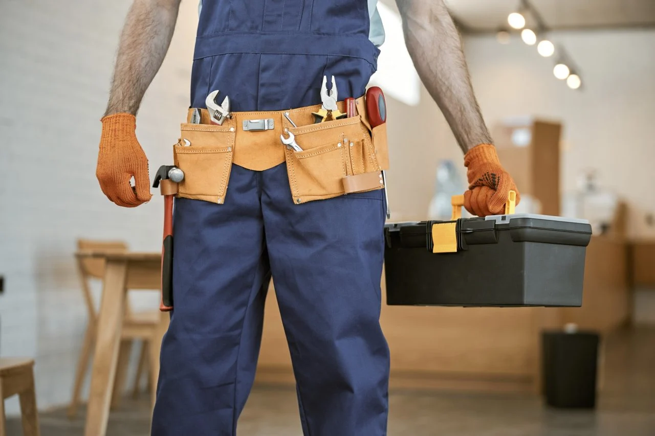Técnico electricista industrial con guantes sosteniendo caja de herramientas para mantenimiento y automatización